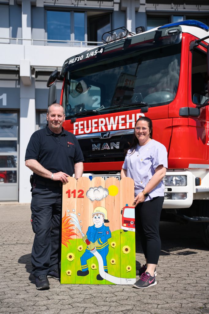 Matthias Schmitt übergibt das Kunstwerk an Sarah Maugeri (Foto: Feuerwehr Kaiserslautern)